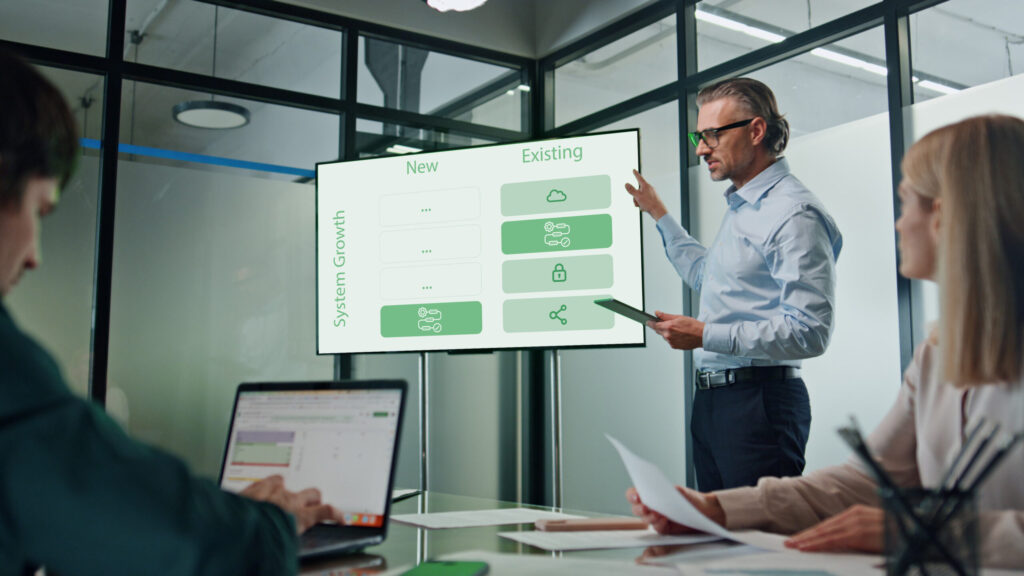 Brauchen Sie wirklich Verinice, HiScout & Co.? – So funktioniert ein ISMS mit Jira und Confluence 13 Ein Berater erklärt an einem Graphen wie Systeme in bestehenden oder neuen Strukturen implementiert werden können.